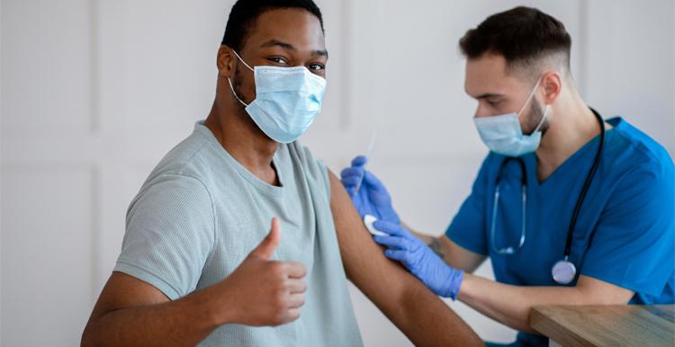 Black man with thumbs up having a vaccine