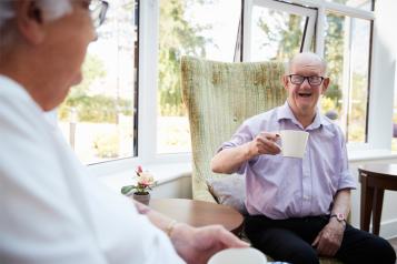 Man talking to an elderly man sitting in a chair